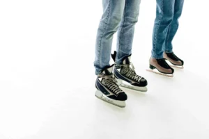 Two people wearing ice skates on rink.